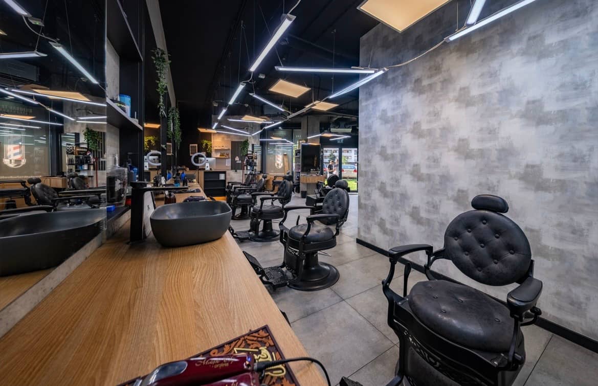 The oak counter running along the wall, with mirrors and black buttoned barber chairs